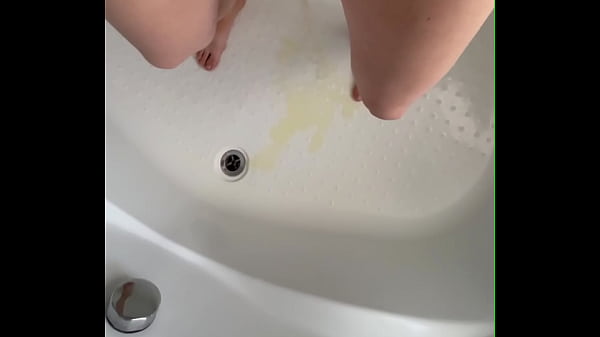 Hairy MILF Elena pisses a tight stream of yellow salty urine while standing at the bottom of the tub.